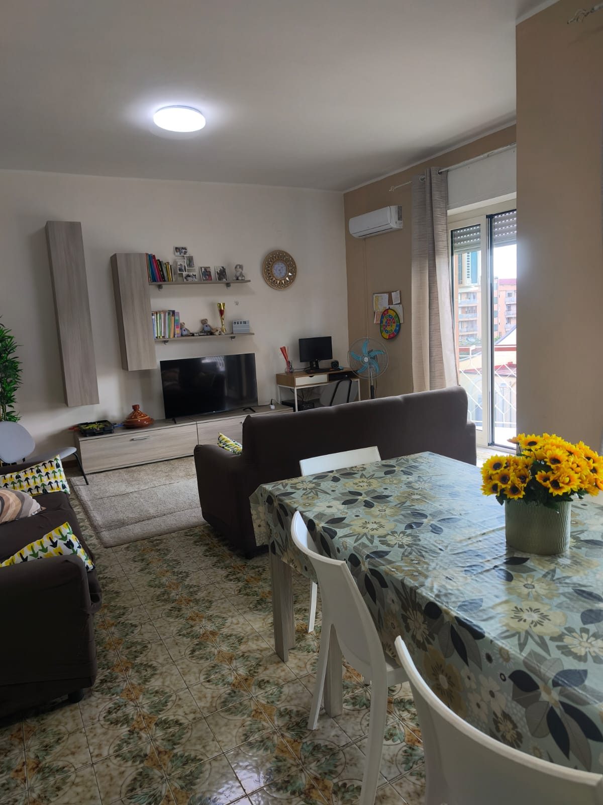 Salotto con divani, TV e tavolo da pranzo decorato con girasoli nella comunità CPA Futura
