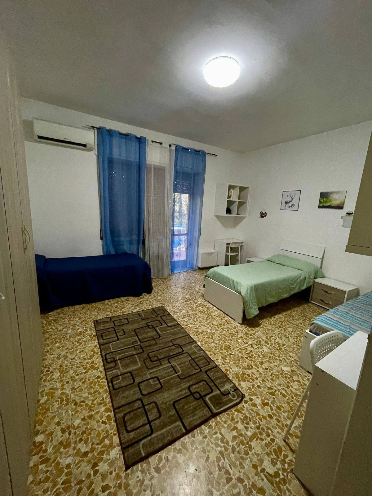 Cameretta con letti singoli blu e verde e tappeto nella comunità I Folletti